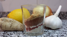 A glass sits on a counter, full of dried spices in layers.