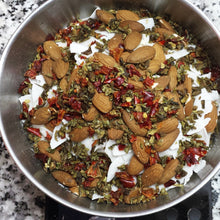 A steel bowl sits on an electric scale, full of the dry ingredients of the TentMeals Almond jalfrezi main meal. Includes almonds, coconut, dried  peppers