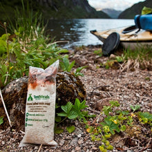 TentMeals Almond jalfrezi 800kcal main meal, leaning against a rock, with a lake and canoe in the background